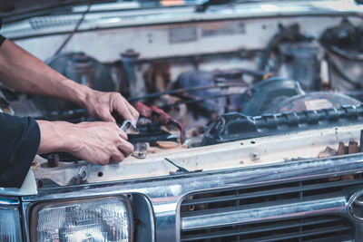 Cropped hands of mechanic repairing car in garage