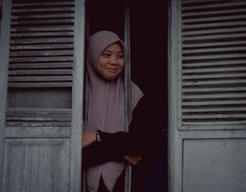 Portrait of young woman standing against wall