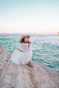 Woman looking at sea against sky during sunset