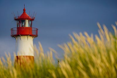 Lighthouse on field against sky