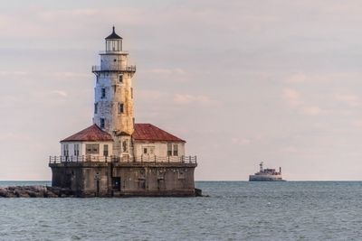 Lighthouse by sea against sky