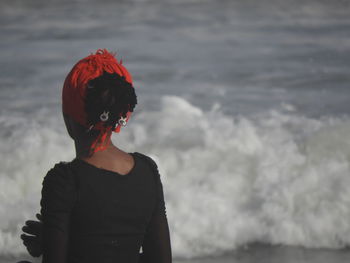 Rear view of woman standing against sea