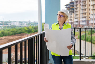 Mid adult woman standing against railing