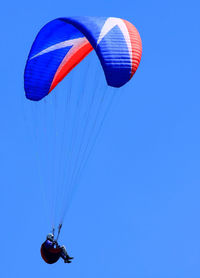 Low angle view of person paragliding against clear blue sky 