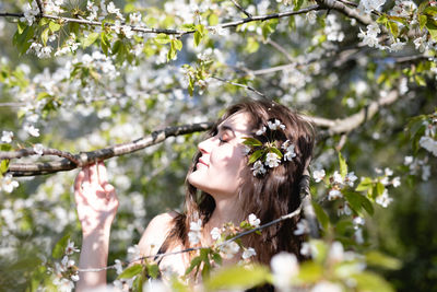 Young woman amidst flowering tree