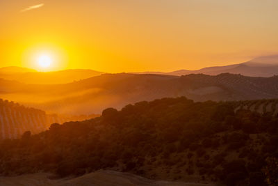 Scenic view of silhouette mountains against orange sky