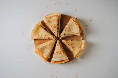 Flat lay of crepes laid out in triangles in a circle on a wooden board	
