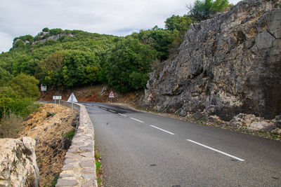 Road amidst trees and plants against sky