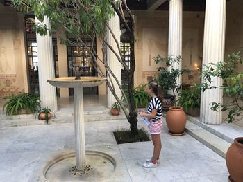 Full length of woman sitting on potted plant