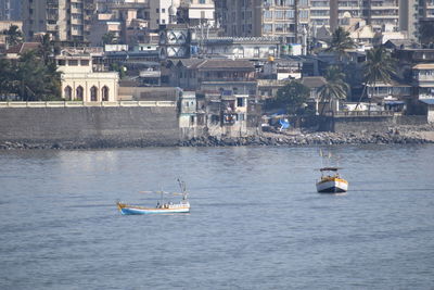 High angle view of sailboat sailing in sea against buildings in city