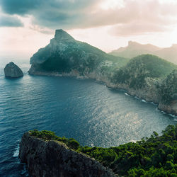 Scenic view of sea by mountains against sky