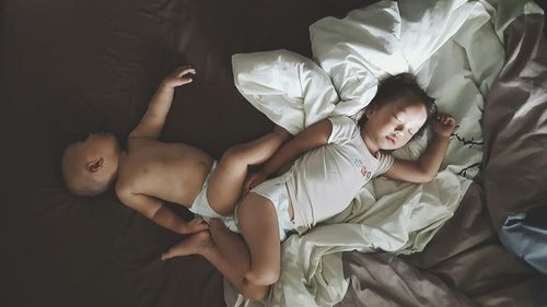 Directly above shot of siblings sleeping on bed