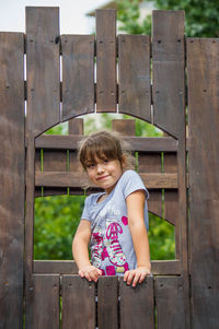 Portrait of boy standing on wooden wall