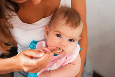 Mother feeding cute baby girl vegetable puree from a spoon. healthy eating nutrition for little kids