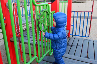 Cute toddler in a winter suit playing at the playground on the beach