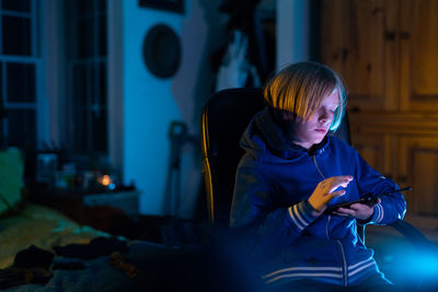 Tween boy sitting in home working on tablet while sitting in chair