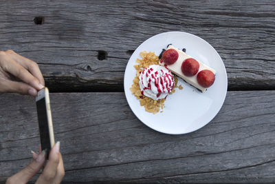 Cropped hands photographing dessert on wooden table