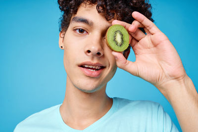 Portrait of man holding fruit against blue background