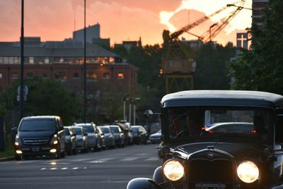 Cars parked on road in front of city during sunset