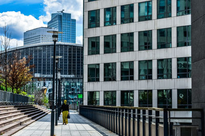 Rear view of woman walking against building in city