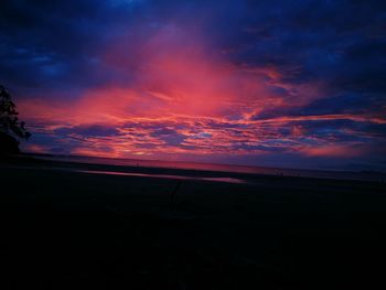 Scenic view of sea against dramatic sky at sunset