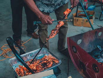 Midsection of man preparing food on barbecue grill