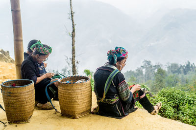 Friends sitting on basket against mountain