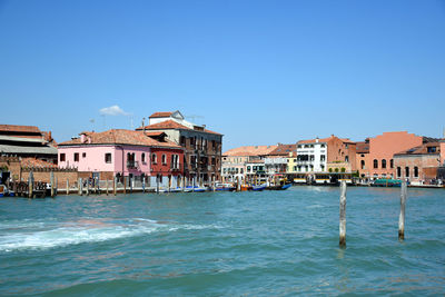 View of buildings by sea against blue sky