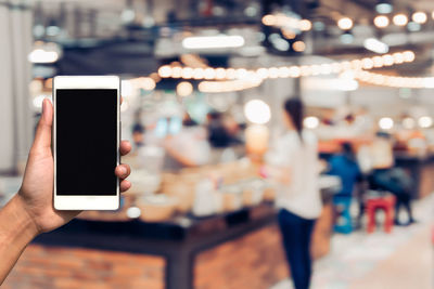 Close-up of hand holding mobile phone at restaurant