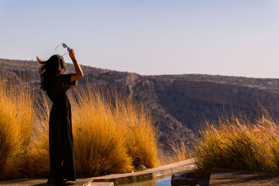 Rear view of woman standing on land against clear sky