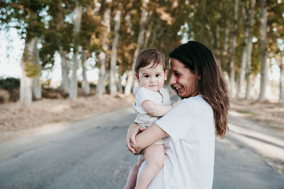 Portrait of mother and daughter standing on tree