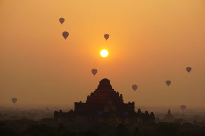 Silhouette of hot air balloons against sky during sunset