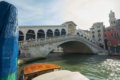 Rialto bridge over river against cloudy sky