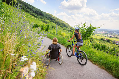 Rear view of people riding bicycle on road against sky