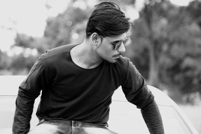 Young man sitting on car