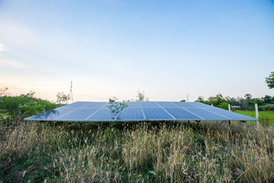 Solar panels on land against sky during sunset