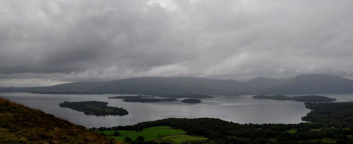 Scenic view of lake and mountains against storm clouds