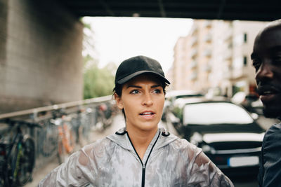 Female athlete talking with sportsman while standing on sidewalk in city