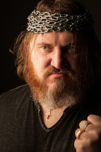 Close-up portrait of man wearing hat against black background