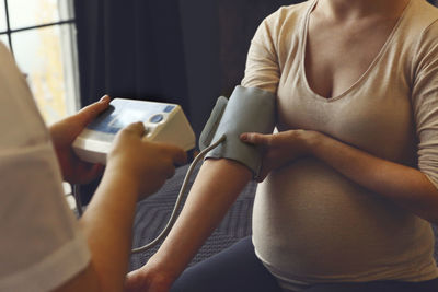 Midsection of pregnant woman checking blood pressure