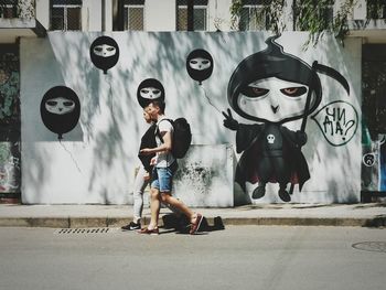 Full length portrait of man standing against graffiti wall