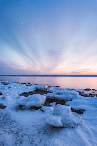 Scenic view of frozen sea against sky at sunset