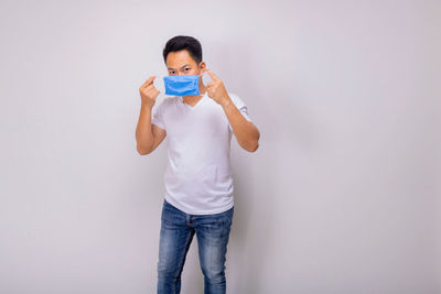 Portrait of man drinking against wall