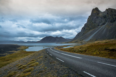 Empty road by mountains against sky