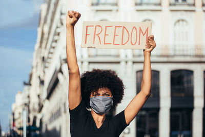 Young woman with arms raised standing in city