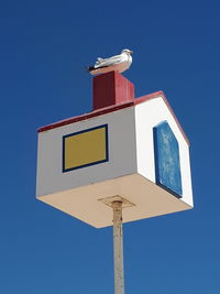 Low angle view of road sign against clear blue sky