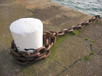 High angle view of chain on mooring bollard at harbor