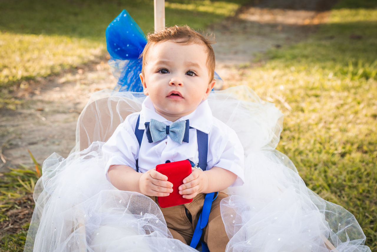 PORTRAIT OF CUTE BOY SITTING ON FIELD