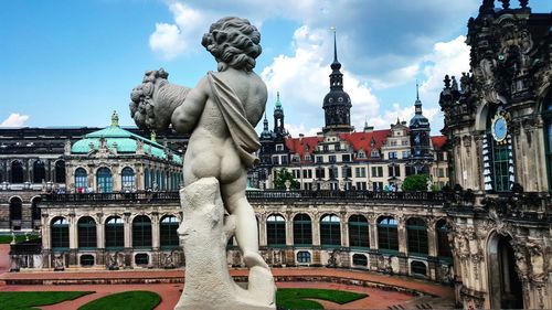 Statue in city against cloudy sky