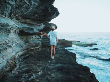 People standing on rock formation in sea